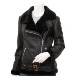 Women's black leather shearling biker jacket with fur collar, asymmetric zipper, zippered pockets, cuffs, and waist belt